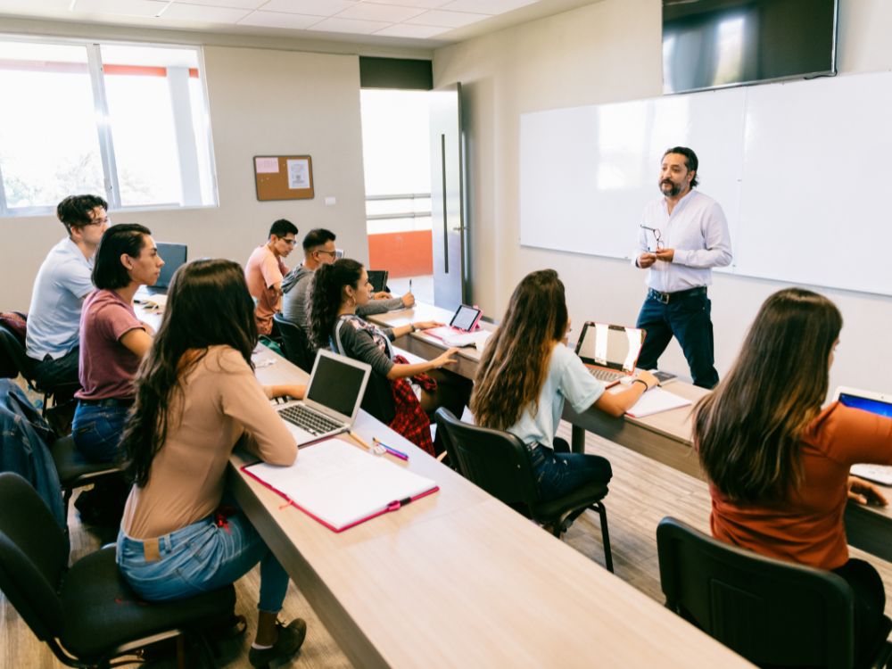 **Texto alt:** Sala de aula universitária com professor ministrando aula para estudantes, representando as principais **cidades universitárias SP** e suas oportunidades de ensino superior.